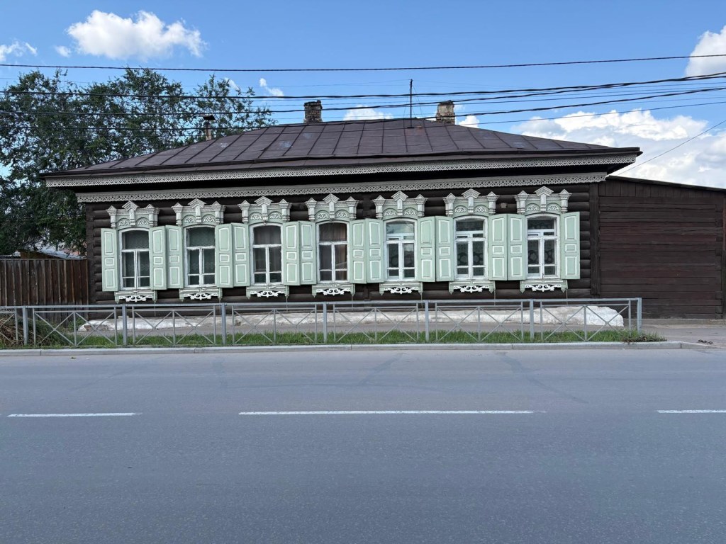Açık yeşil pencere pervazları ve oyma süslemeleriyle Ulan-Ude’de geleneksel ahşap ev