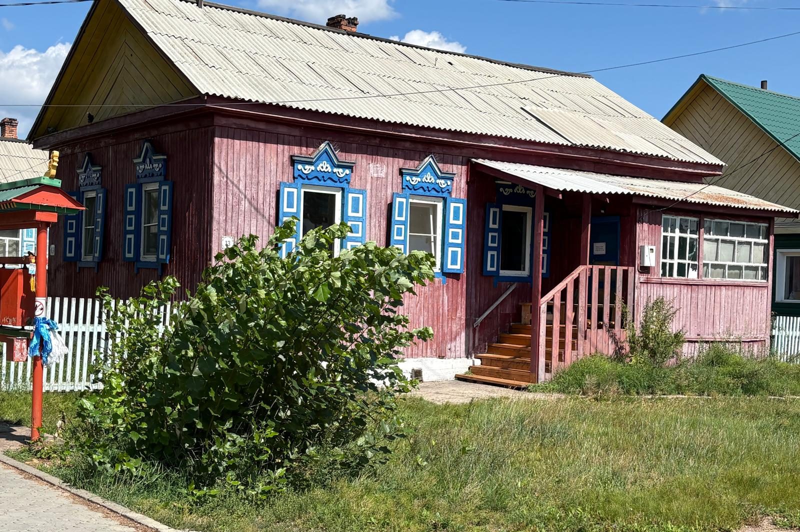 A traditional wooden house with blue window decorations in the Ivolginsky Datsan complex